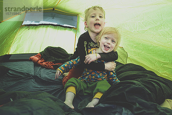 Porträt von Geschwistern  die zusammen in einem Zelt spielen