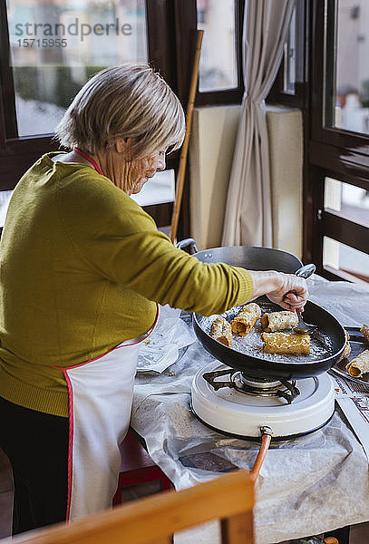 Ältere Frau bereitet spanisches Weihnachtsgebäck Pestinos