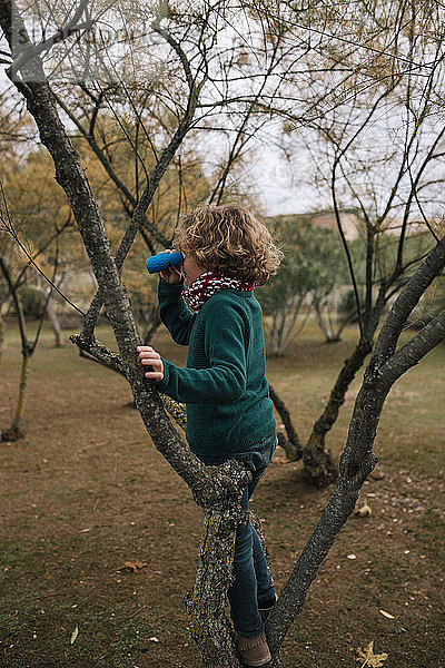 Junge im Herbst  der etwas mit dem Fernglas beobachtet