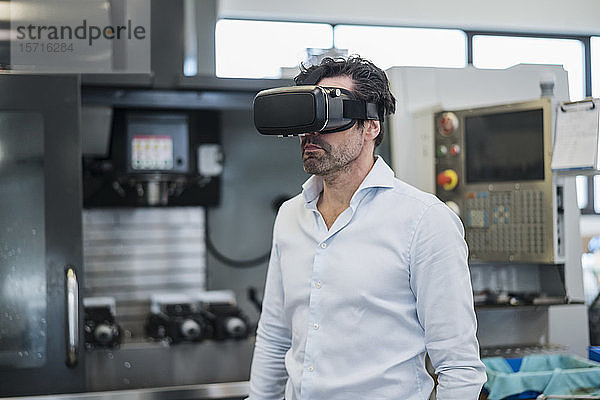 Geschäftsmann mit VR-Brille in einer Fabrik