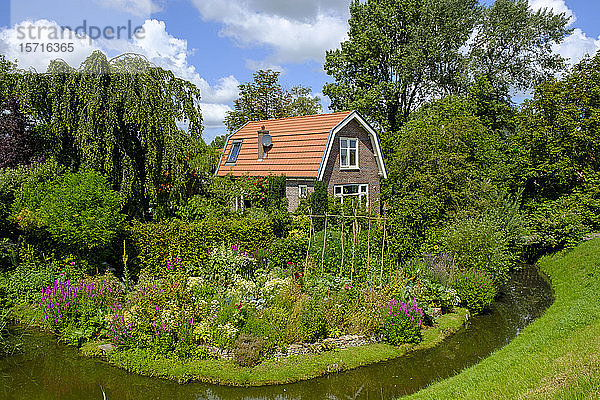 Niederlande  Nordholland  Hoorn  Ijsselseegraben  der sich vor dem blühenden Garten eines Landhauses erstreckt