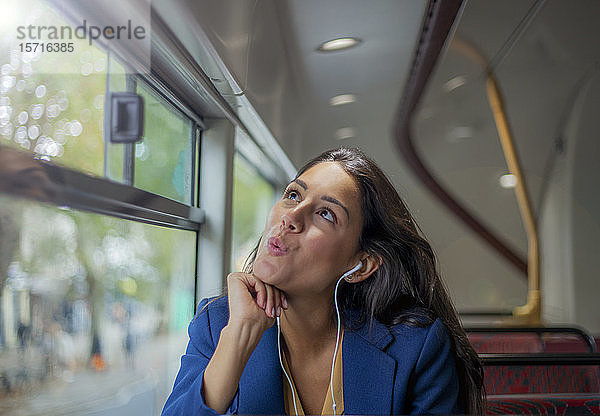 Junge Frau  die im Bus mit Kopfhörern Musik hört