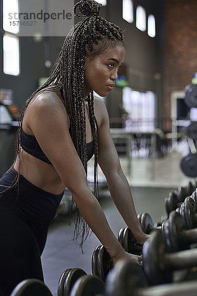 Sportlerin wählt Gewichte für das Training im Fitnessstudio