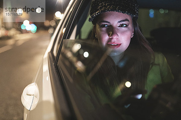 Frau  die nachts auf dem Rücksitz eines Autos in der Stadt sitzt