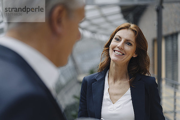 Porträt einer lächelnden Geschäftsfrau im Gespräch mit einem Geschäftsmann im Amt