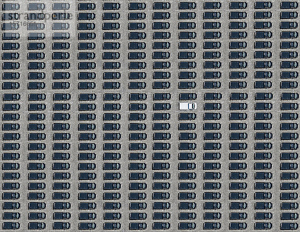 Luftbild eines einzelnen weißen Autos  das zwischen ausschließlich schwarzen Autos geparkt ist