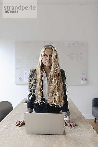 Porträt einer jungen Geschäftsfrau  die Yoga praktiziert  auf einem Schreibtisch im Büro