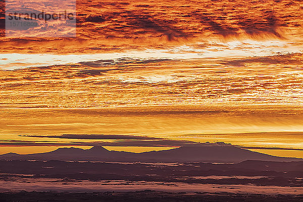 Neuseeland  Dramatischer Sonnenaufgang über dem Tongariro-Nationalpark mit den Silhouetten von Vulkanen in der Ferne