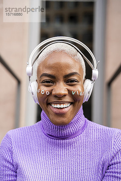 Porträt einer weisshaarigen Frau mit weissen Kopfhörern und Aufklebern im Gesicht  gute Laune