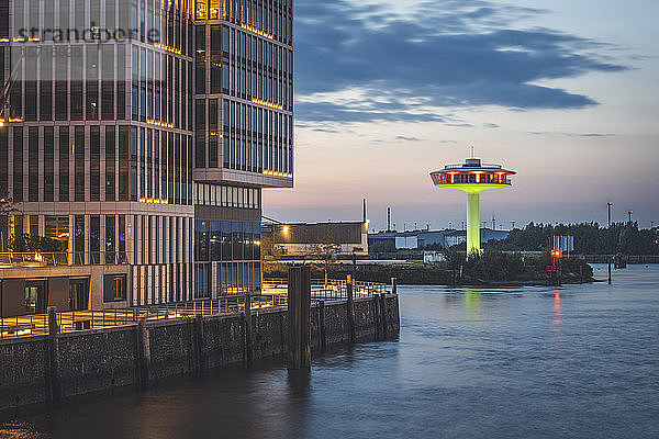 Deutschland  Hamburg  Gebäude am Wasser in der Abenddämmerung mit Leuchtturm Null im Hintergrund