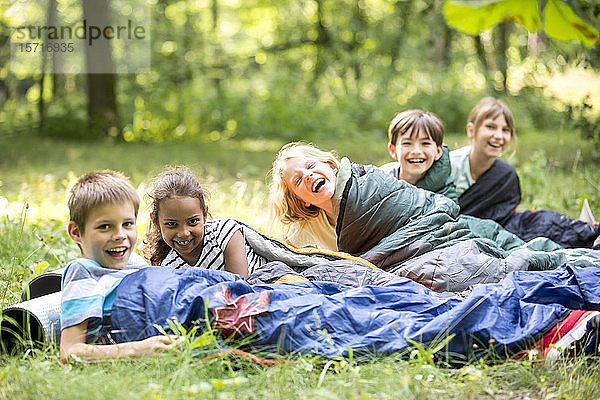 Schulkinder  die im Wald zelten und in Schlafsäcken liegen
