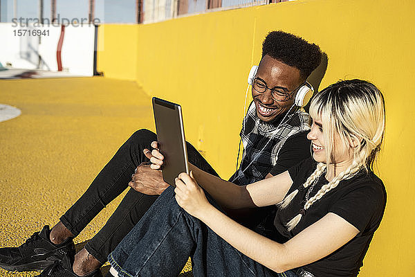 Junges Paar vergnügt sich mit Kopfhörern und digitalem Tablet im Freien