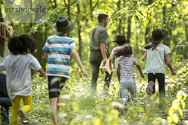 Schulkinder  die mit ihrem Lehrer im Wald spazieren gehen