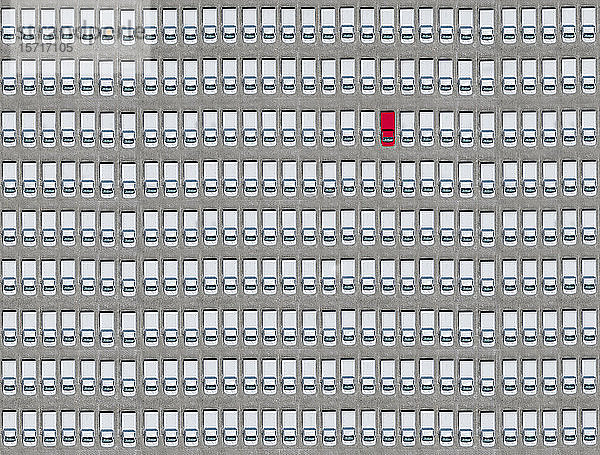 Luftaufnahme eines einzelnen roten Autos  das inmitten nur weißer Autos geparkt ist