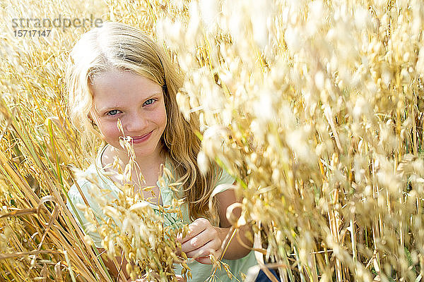 Lächelndes Mädchen steht im reifen Weizenfeld