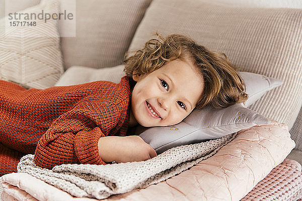 Porträt eines lächelnden Mädchens  das zu Hause auf der Couch liegt