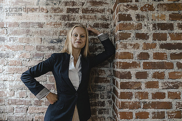 Porträt einer selbstbewussten jungen Geschäftsfrau an einer Ziegelmauer