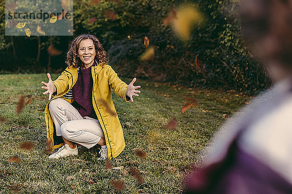 Glückliche Mutter wartet im Herbst mit offenen Armen auf ihre Tochter im Freien