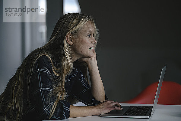 Lässige junge Geschäftsfrau mit Laptop im Büro