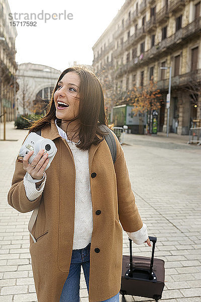 Glückliche junge Frau mit Koffer und Kamera in der Stadt unterwegs  Barcelona  Spanien