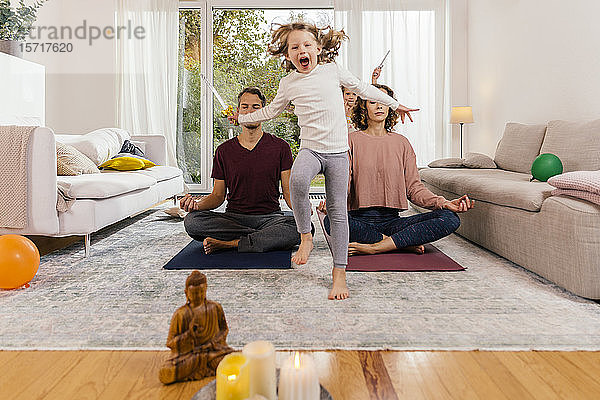 Überschwängliches Mädchen mit zu Hause meditierenden Eltern