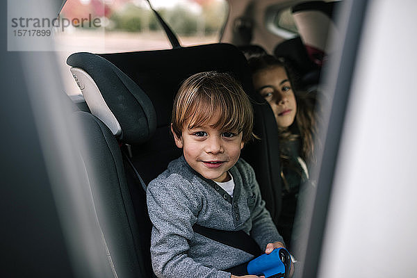 Porträt eines lächelnden kleinen Jungen  der im Kindersitz im Auto sitzt