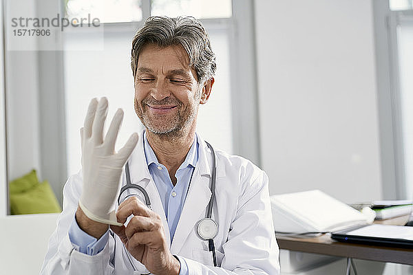 Arzt  der in seiner Praxis Schutzhandschuhe anzieht