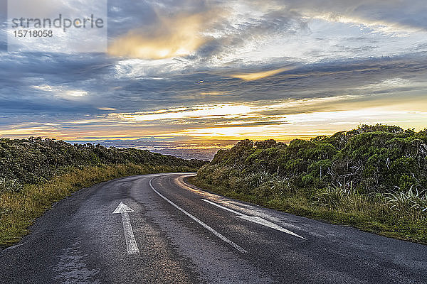 Neuseeland  Wolken über leerer Asphaltstrasse im Egmont Nationalpark in der Abenddämmerung