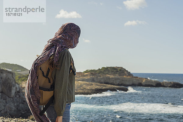 Junge Frau an der Küste mit Tuch um das Gesicht  Ibiza  Spanien