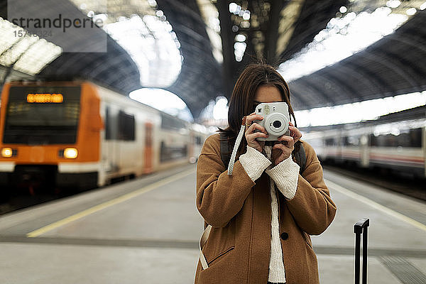 Junge Frau beim Fotografieren mit Kamera am Bahnhof
