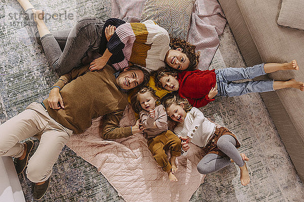 Glückliche Familie mit drei Töchtern  die zu Hause auf Decken liegen