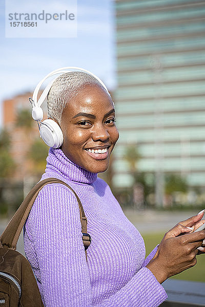 Porträt einer weißhaarigen Frau mit weißen Kopfhörern  die in der Stadt Musik hört