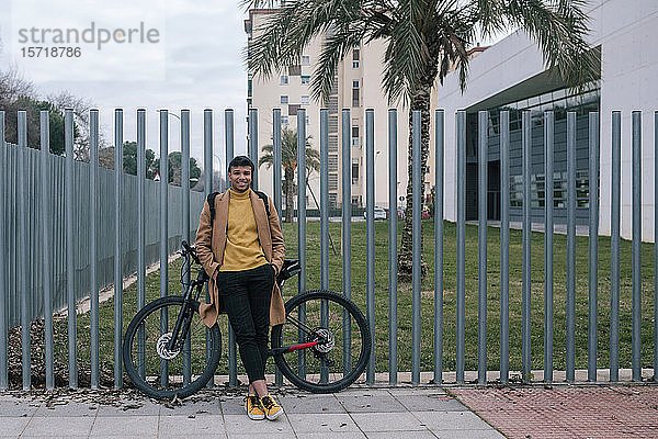 Porträt eines lächelnden jungen Mannes mit Fahrrad in der Stadt
