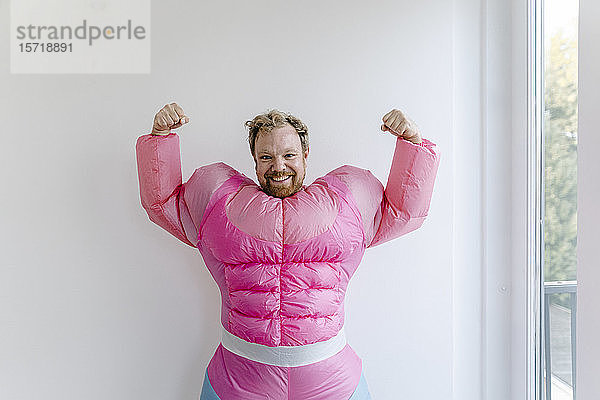 Stolzer Mann in rosa Bodybuilder-Kostüm  der seine Muskeln spielen lässt