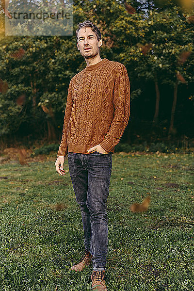 Porträt eines Mannes  der im Herbst auf einer Wiese steht