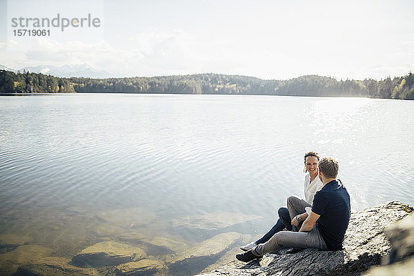 Glückliches Paar am Seeufer sitzend  Forstsee  Kärnten  Österreich