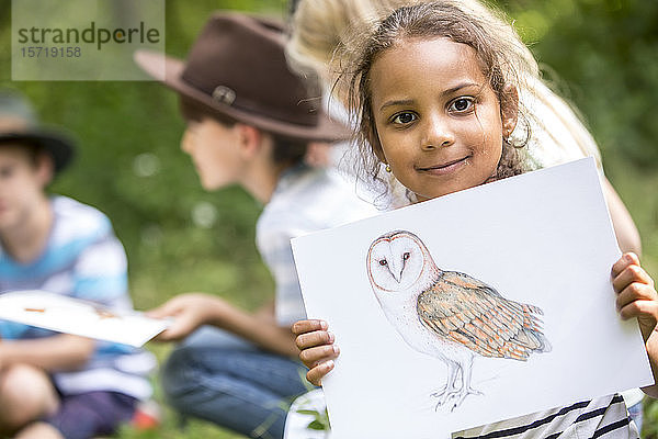 Schulkinder lernen etwas über Tierarten  Mädchen hält Bild eines Vogels