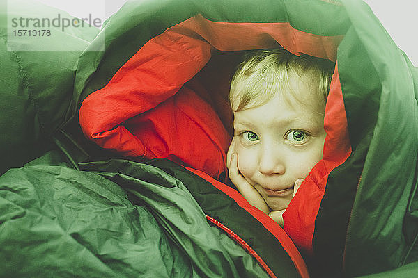 Porträt eines blonden kleinen Jungen in einem Schlafsack