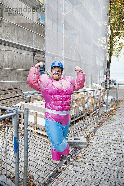 Porträt eines stolzen Mannes mit rosa Bodybuilder-Kostüm und Schutzhelm auf der Baustelle