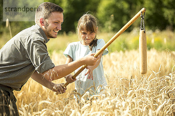 Kinder lernen  wie man Weizen auf dem Feld schleudert