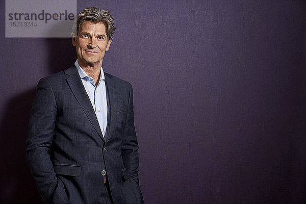 Porträt eines selbstbewussten Geschäftsmannes vor einer violetten Wand