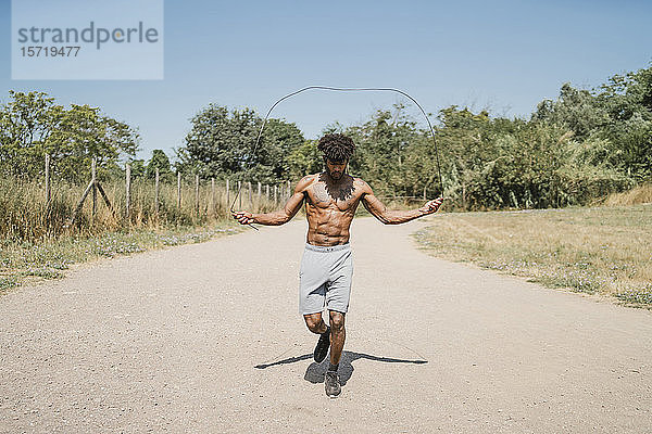 Junger Mann beim Seilspringen während des Trainings in einem Park