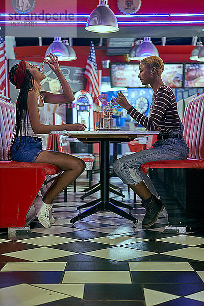 Zwei Frauen teilen sich einen Milchshake auf dem Tisch eines amerikanischen Restaurants