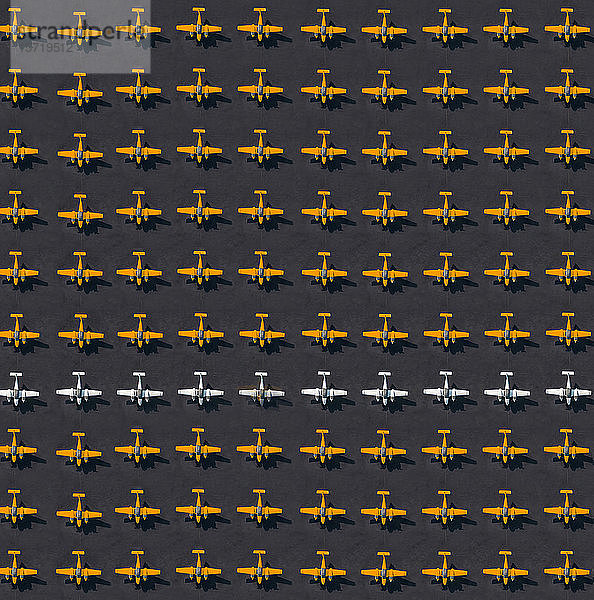 Luftbild einer Reihe weißer Flugzeuge inmitten nur oranger Flugzeuge