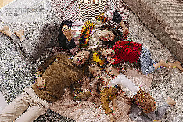 Glückliche Familie mit drei Töchtern  die zu Hause auf Decken liegen