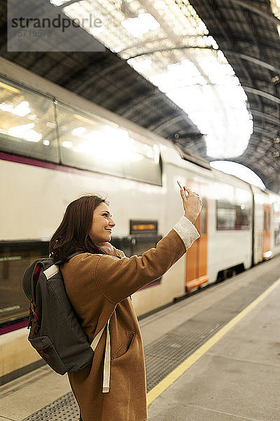 Junge Frau beim Selfie am Bahnhof
