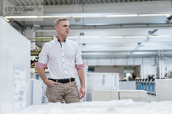 Mann mit weißem Hemd in einer Fabrik  der sich umsieht