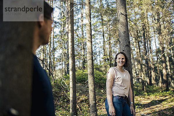 Lächelnde Frau sieht Mann im Wald an