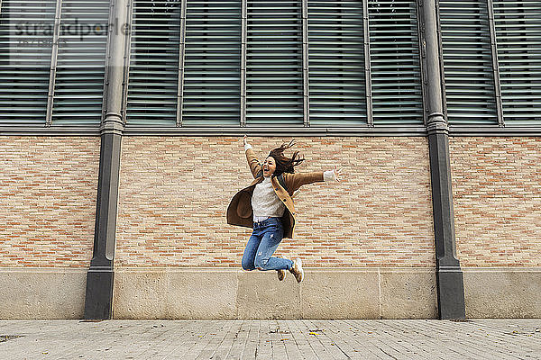 Aufgeregte junge Frau springt in der Stadt