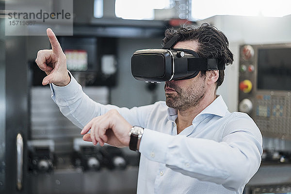 Geschäftsmann mit VR-Brille in einer Fabrik